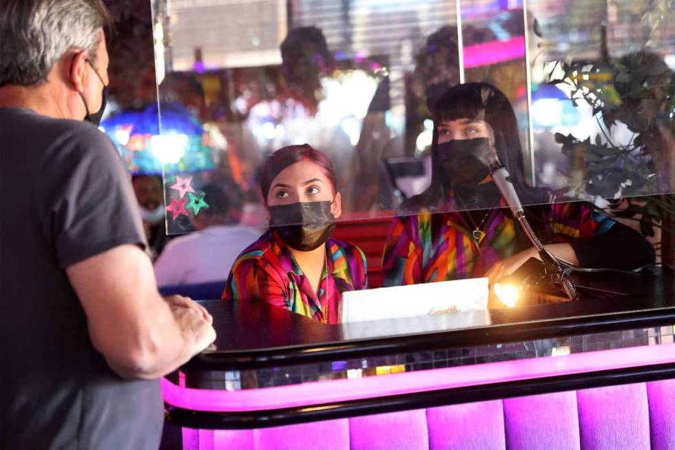 Hostesses Cristina Montiel and Esmeralda Valencia assist a customer, far left, at the Peppermil ...