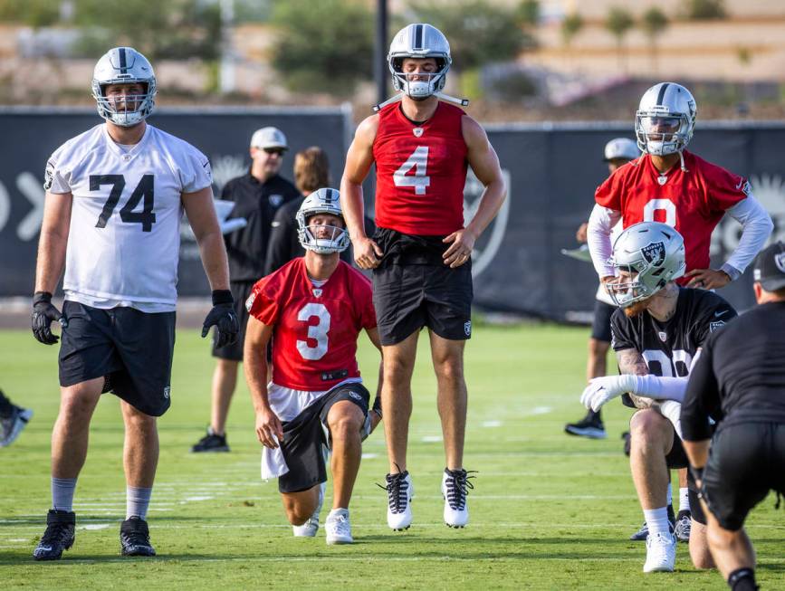 Raiders quarterback Derek Carr (4) jumps in the air while warming up with quarterback Nathan Pe ...