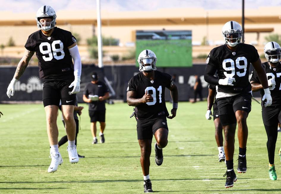 Raiders defensive ends Maxx Crosby (98), Yannick Ngakoue (91) and Clelin Ferrell (99) warm up d ...