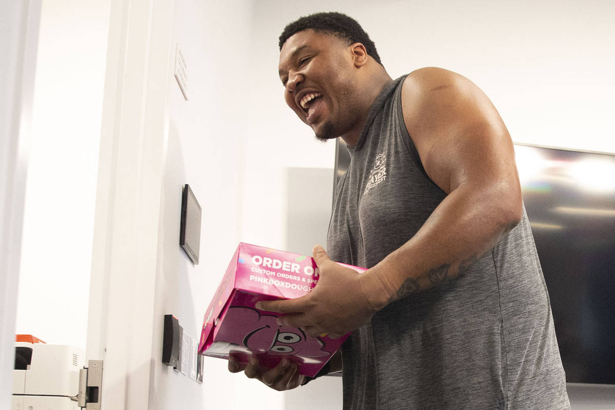Raiders offensive tackle Denzelle Good grabs his box of donuts as he leaves a news conference o ...