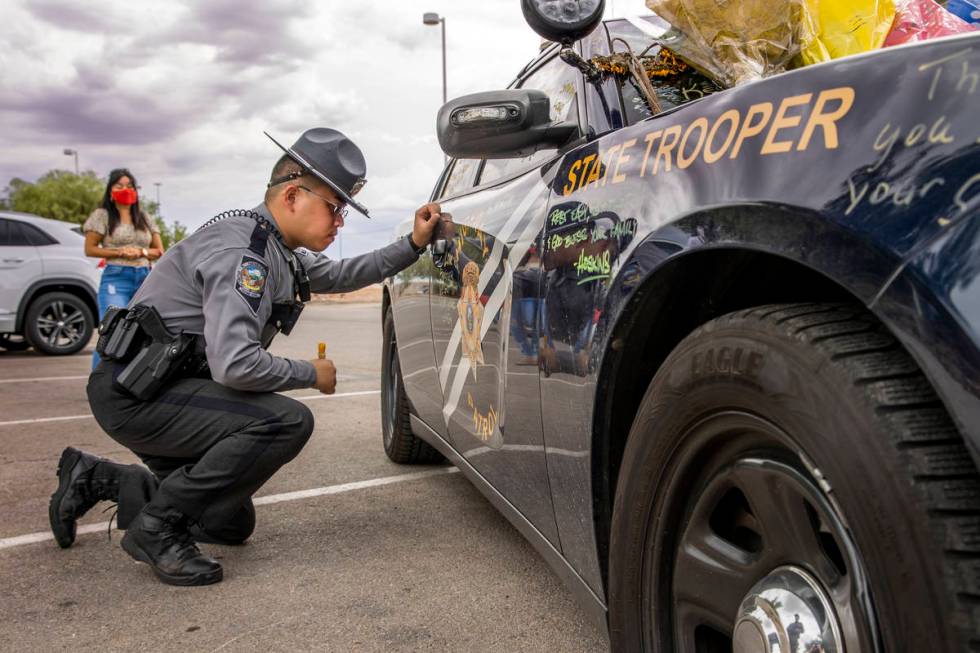 Nevada Highway Patrol trooper Noah Villa takes a quiet moment after signing car #203 driven by ...