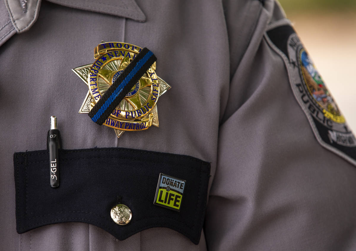 Nevada Highway Patrol trooper Noah Villa wears a black band on his badge in remembrance of fell ...