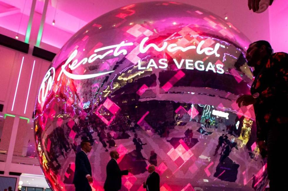 People walk by the illuminated sphere in The District during the opening night of Resorts World ...