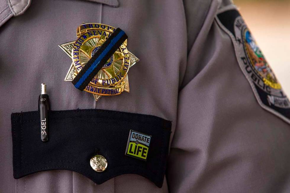 Nevada Highway Patrol Trooper Noah Villa wears a black band on his badge in remembrance of fell ...