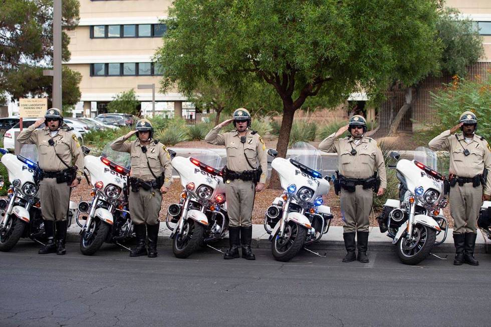 Las Vegas police officers salute to a procession moving the body of slain Nevada Highway Patrol ...