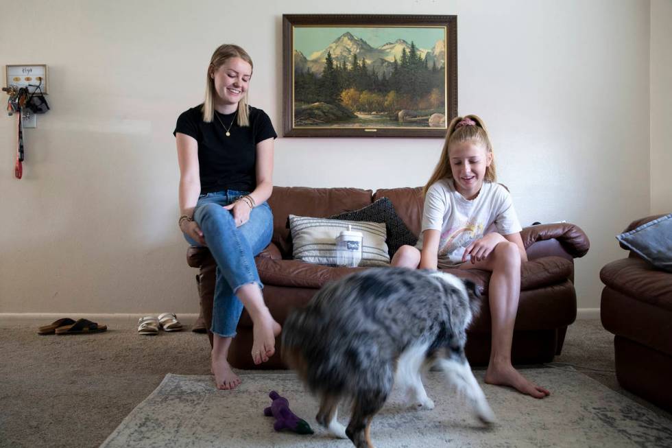 Kylee Tobler and her little sister, Anni, play with her dog, Benny, in the living room of her B ...