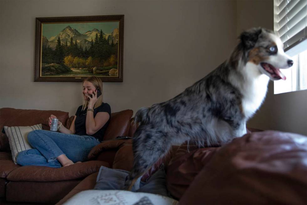 Kylee Tobler speaks with her mom on the phone while her dog, Benny, looks out the living room w ...