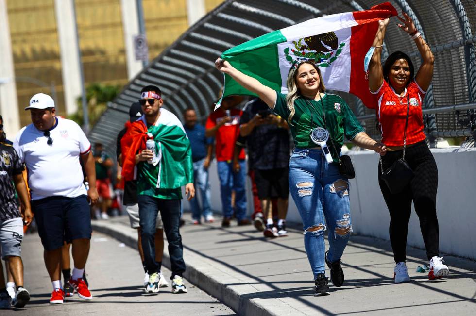 Estefani Cruz, left, and Cristal Iglesias hold up the Mexico flag as they cross a bridge to go ...