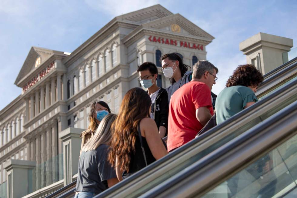 Visitors to the Las Vegas Strip ride escalators with Caesars Palace in the background on Friday ...