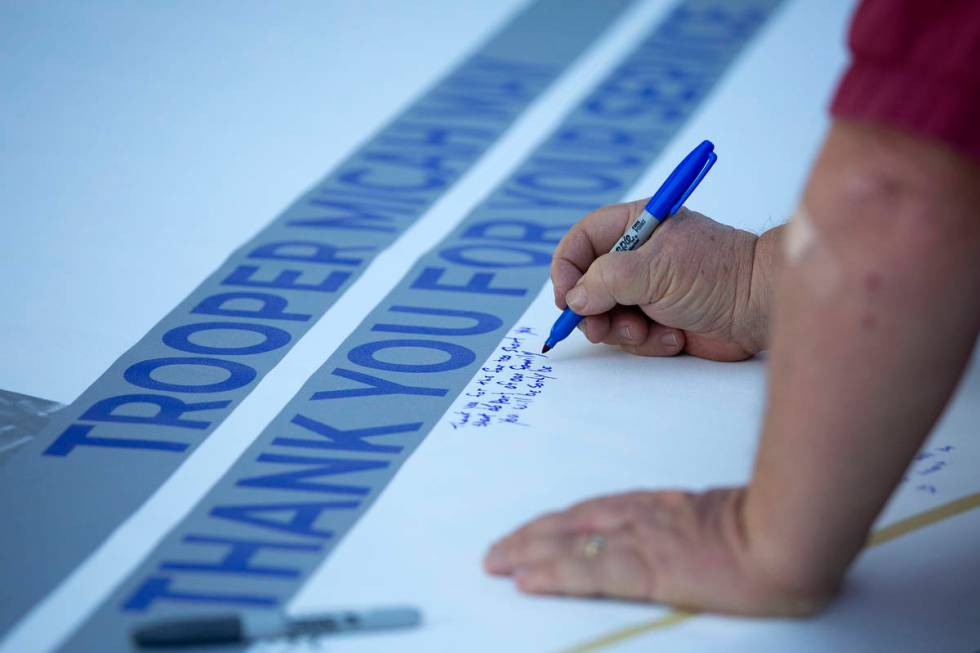 Family, friends and colleagues sign a banner for fallen Nevada Highway Patrol trooper Micah May ...