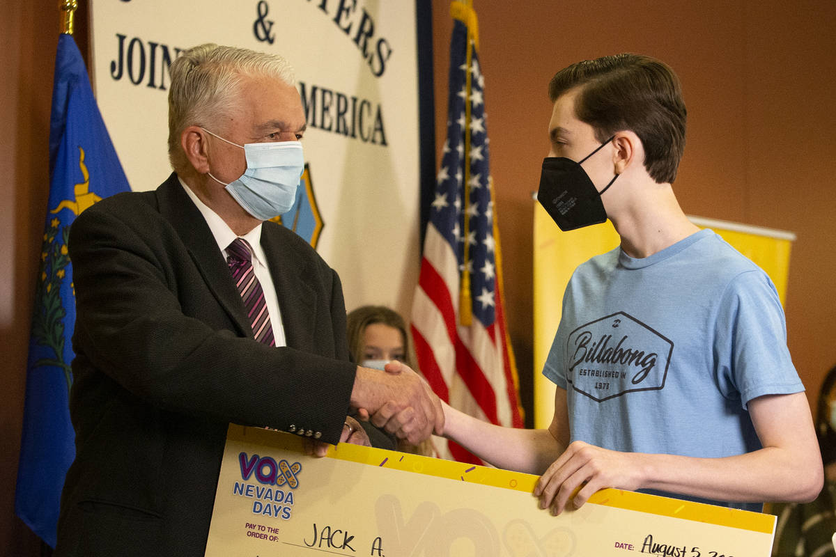 Jack A. shakes Gov. Steve Sisolak's hand after winning a $20,000 college savings plan during th ...