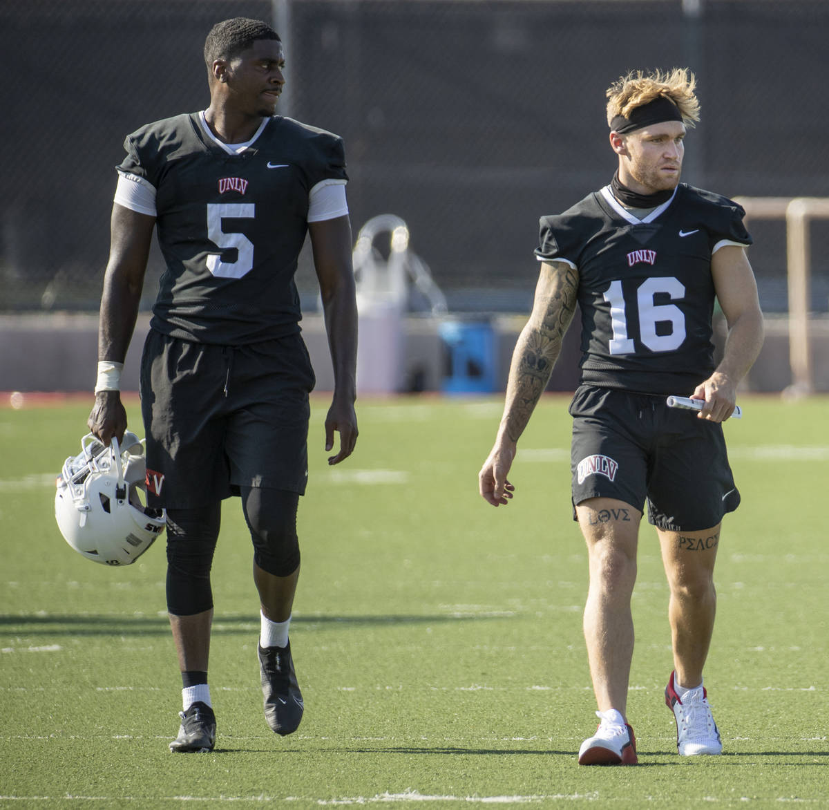 UNLV quarterbacks Justin Rogers (5) and Tate Martell (16) walk up the field during football tea ...