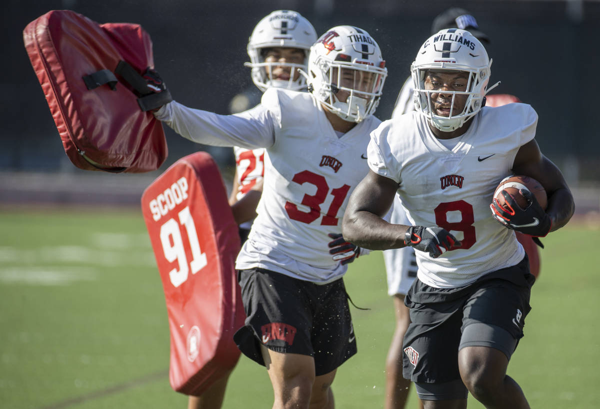 UNLV running back Charles Williams (8) runs past teammate Josh Tihada (31) after hitting a pad ...