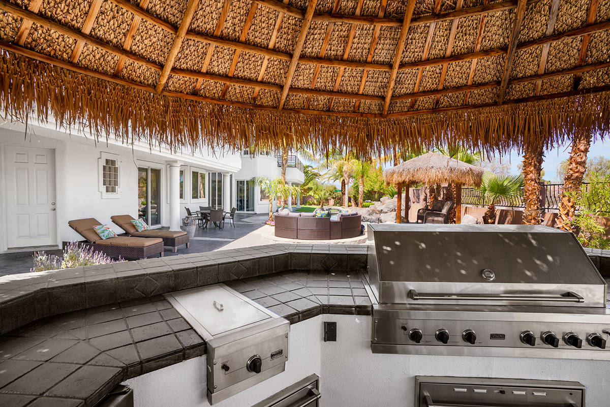The integrated exterior U-shaped kitchen features a 60-inch grill and full round bar seating sh ...