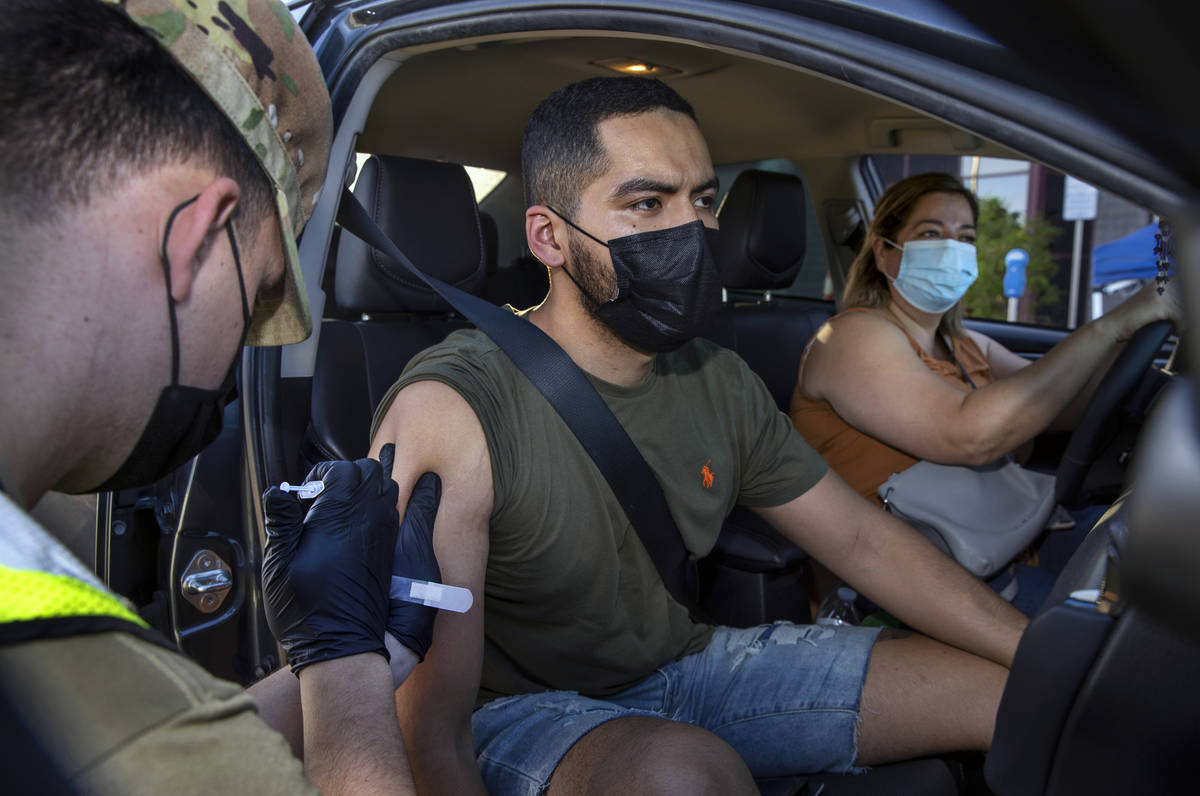 Nevada National Guard SPC Austin Czarnecki gives a COVID-19 vaccination to Luis Gerardo with Hi ...