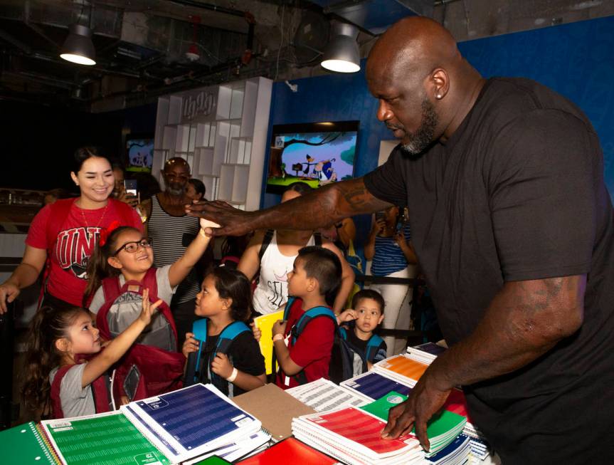 Isabella Hidalgo, 7, center, gives a high-five to former NBA star Shaquille O'Neal, while her s ...