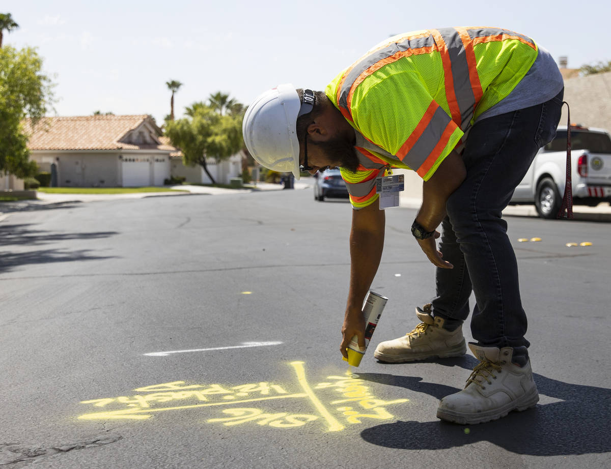 Jacob Olim, locate technician for Stake Center, marks the location of an underground gas line, ...