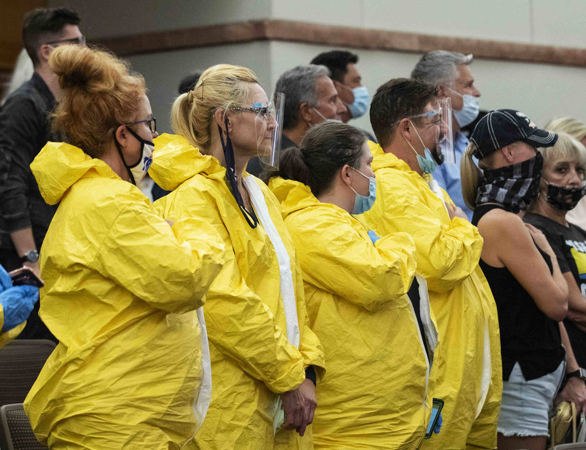 Protesters, including Norma Scurlock, left, wear hazmat suits as they protest against a COVID-1 ...