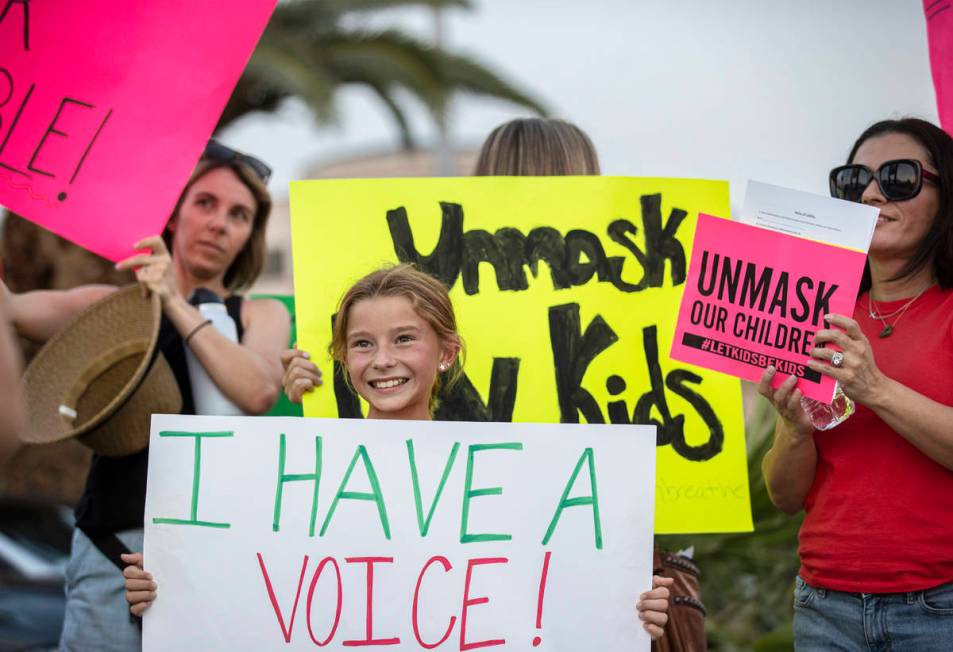 Ali Petersen, middle, 10, holds a sign opposing the mask mandate for Clark County School Distri ...