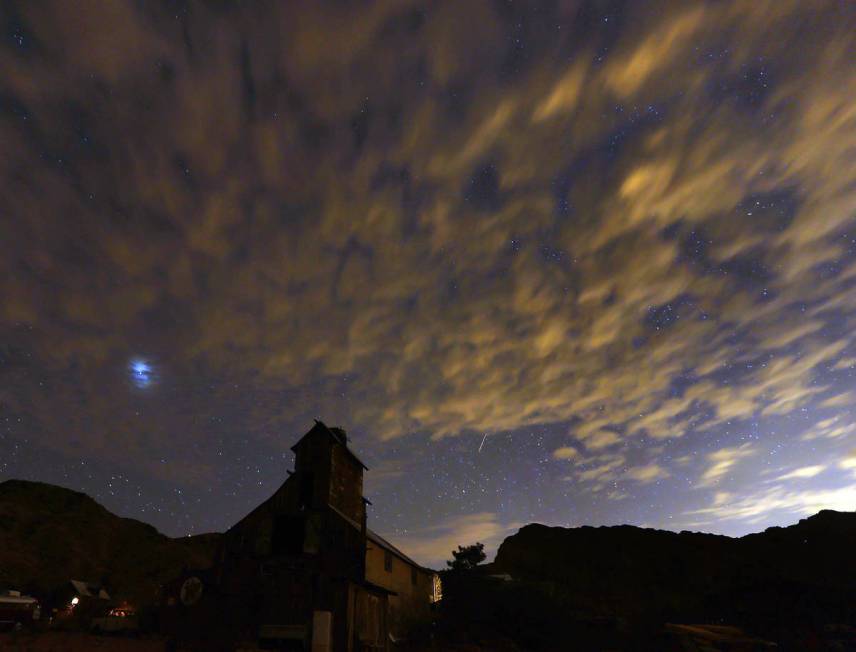 A meteor streaks across the early morning sky over an old barn in Nelson during the Perseids on ...