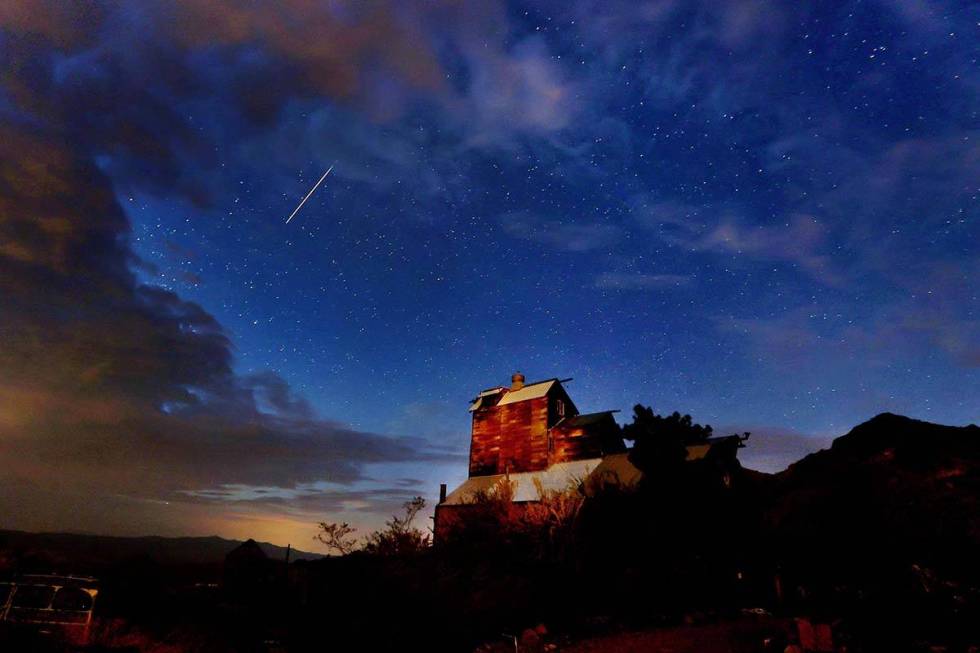 A meteor streaks across the early morning sky over an old barn in Nelson during the Perseids on ...