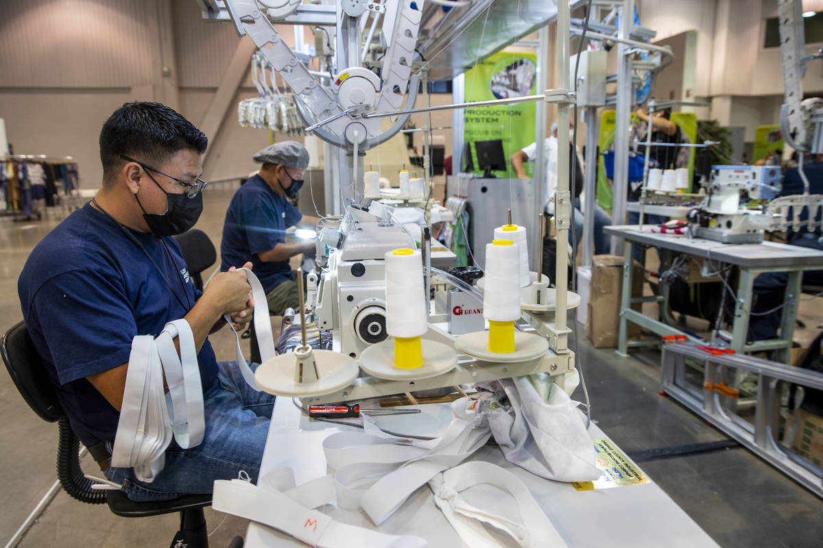 Virginio Matul, left, prepares to sew on another elastic band while helping to display a Unit P ...