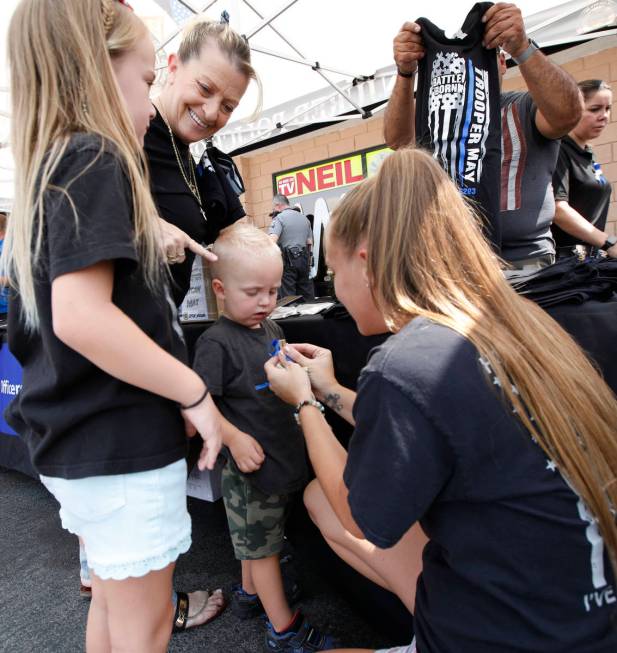 Porsche Sepanek of Las Vegas, right, pins a blue ribbon to the shirt of her son Cayman, 2, cent ...