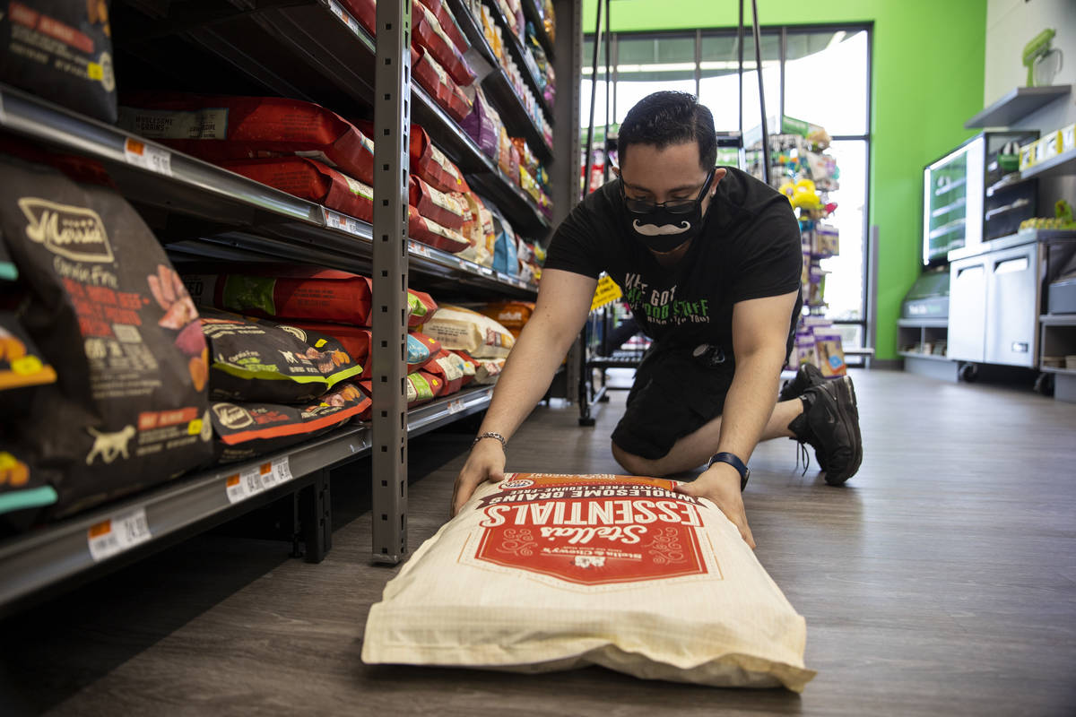 Shift leader Ely Garcia stocks dog food at Pet Supplies Plus, owned by local entrepreneur and f ...