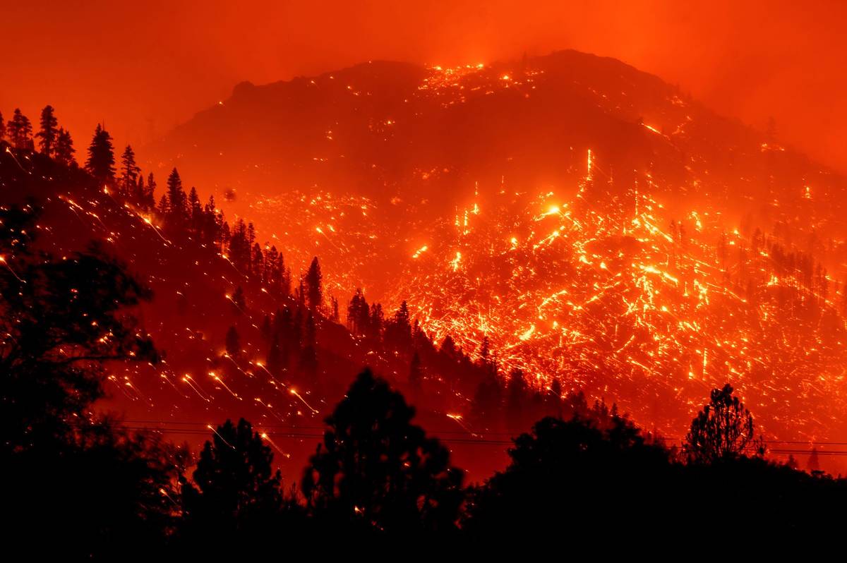 Seen in a long exposure photograph, embers light up hillsides as the Dixie Fire burns near Milf ...
