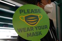 A stadium worker holds up a sign for people to wear face masks before a baseball game between t ...