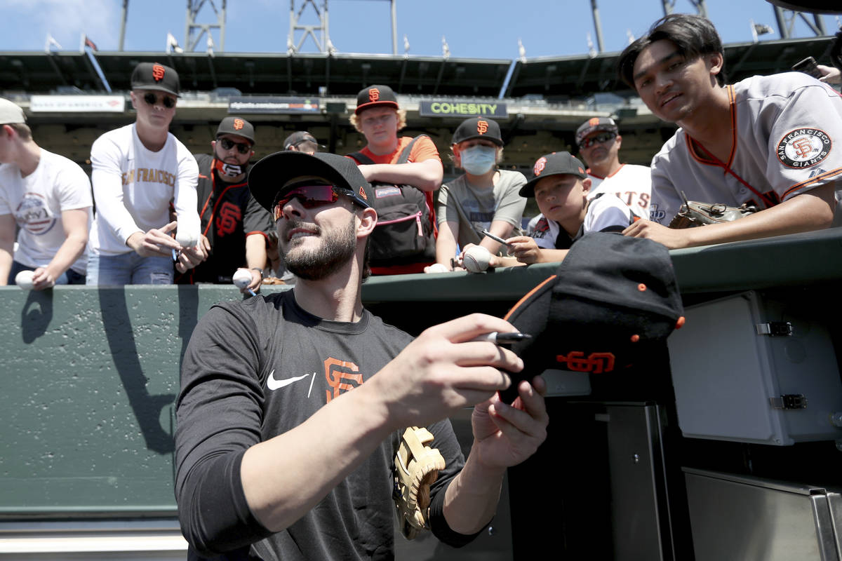 San Francisco Giants' Kris Bryant gives autographs to fans prior to a baseball game against the ...