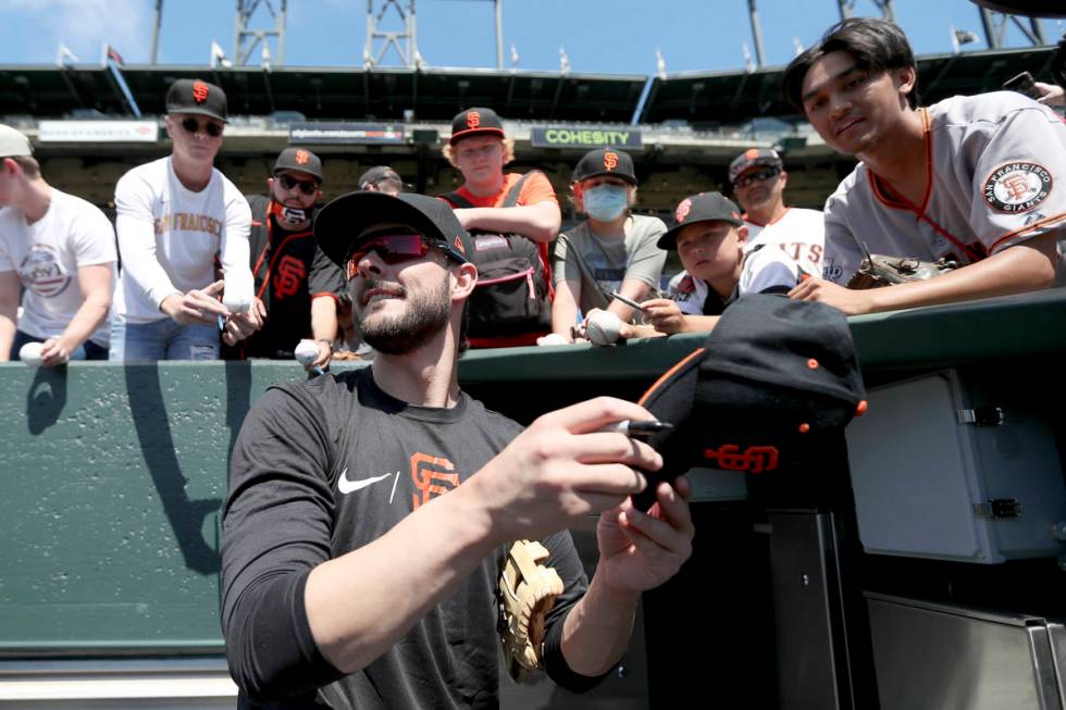 San Francisco Giants' Kris Bryant gives autographs to fans prior to a baseball game against the ...