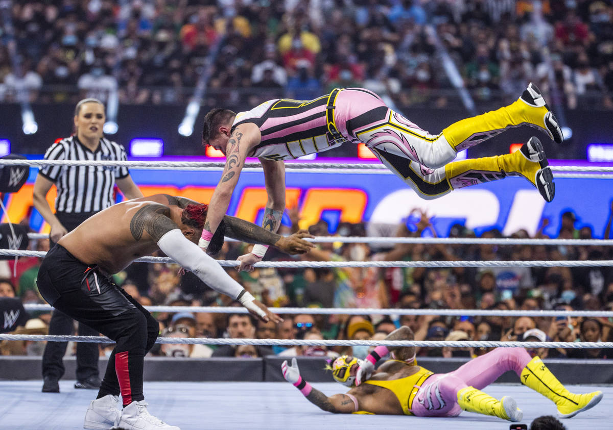 Jimmy Uso, left, has Rey Mysterio, top right, jump down on top of him with Dominik Mysterio bel ...