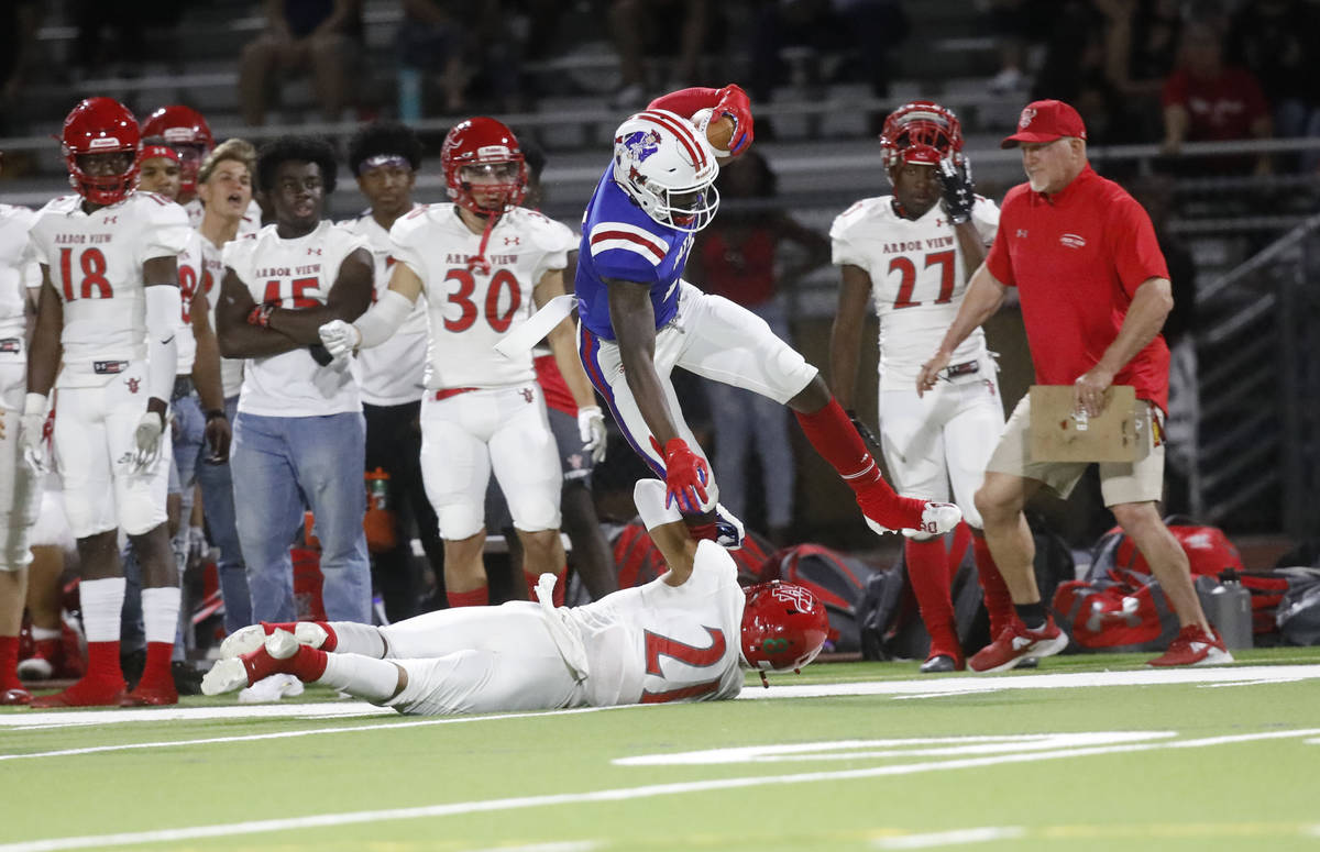 Liberty High School's Germie Bernard (2), center, jumps over Arbor View High School's Aiden Pow ...