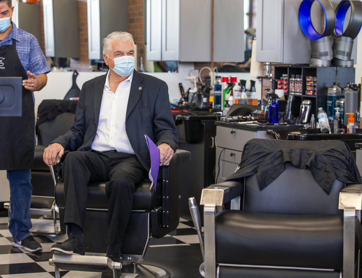 Gov. Steve Sisolak, center, tries out one of the chairs during a tour by owner Paul Madrid of t ...