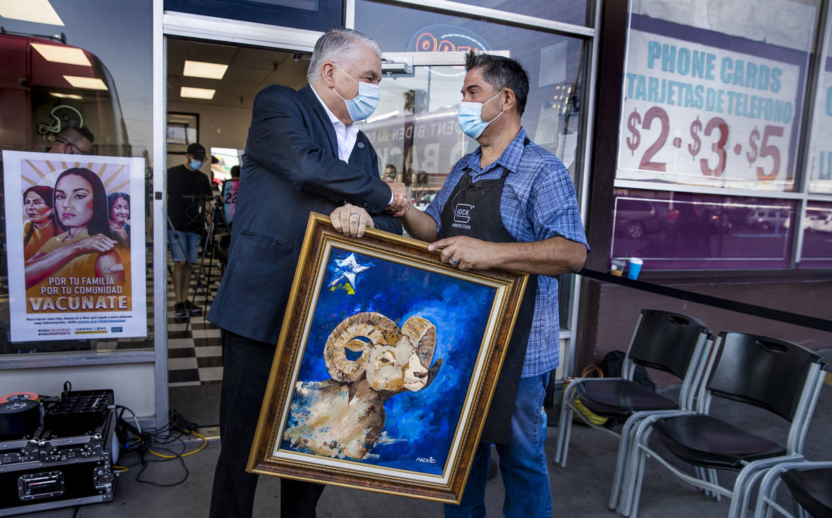 Gov. Steve Sisolak, left, thanks owner Paul Madrid for a tour and a painting he made for the go ...