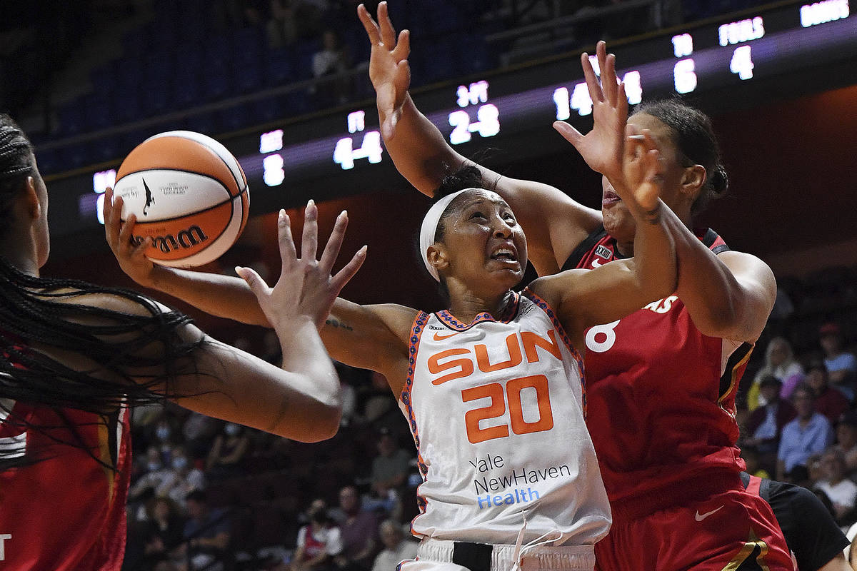 Connecticut Sun's Briann January (20) up for a shot between Las Vegas Aces' Liz Cambage (8) and ...
