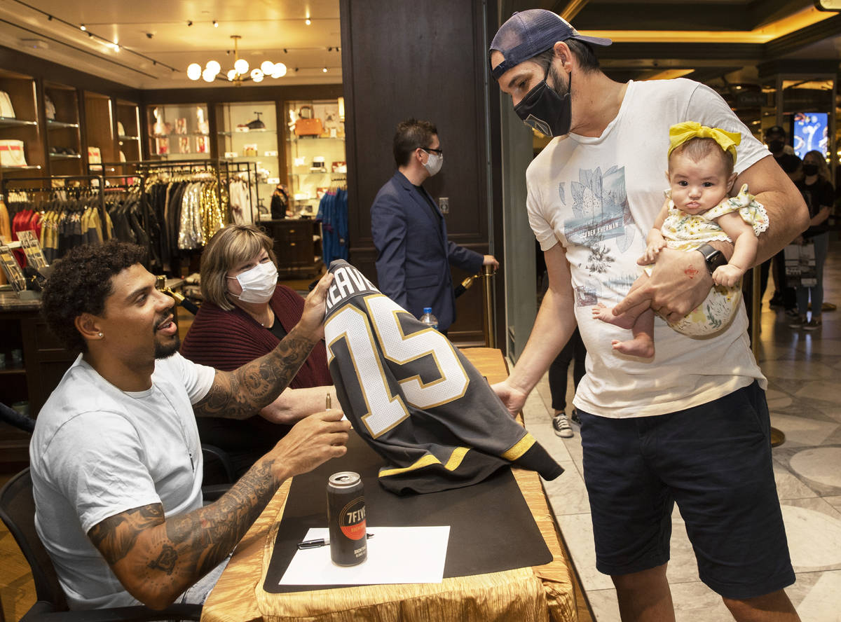 Former Golden Knights player Ryan Reaves, left, signs a jersey for Tas Cofer with daughter Jade ...