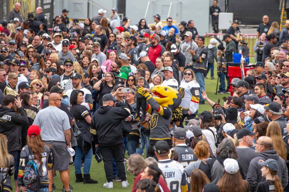 Chance the Gila Monster holds a baby dressed in team gear up to the crowd during the Vegas Gold ...