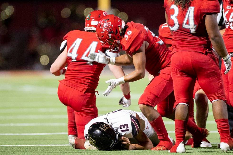 Arbor View's Marcus Young (36) looks over Faith Lutheran's Rylan Walter (13) after getting a ta ...