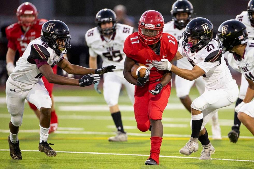 Arbor Views (27) runs the ball under pressure from Faith Lutheran's Vicentico Pringle (27) and ...