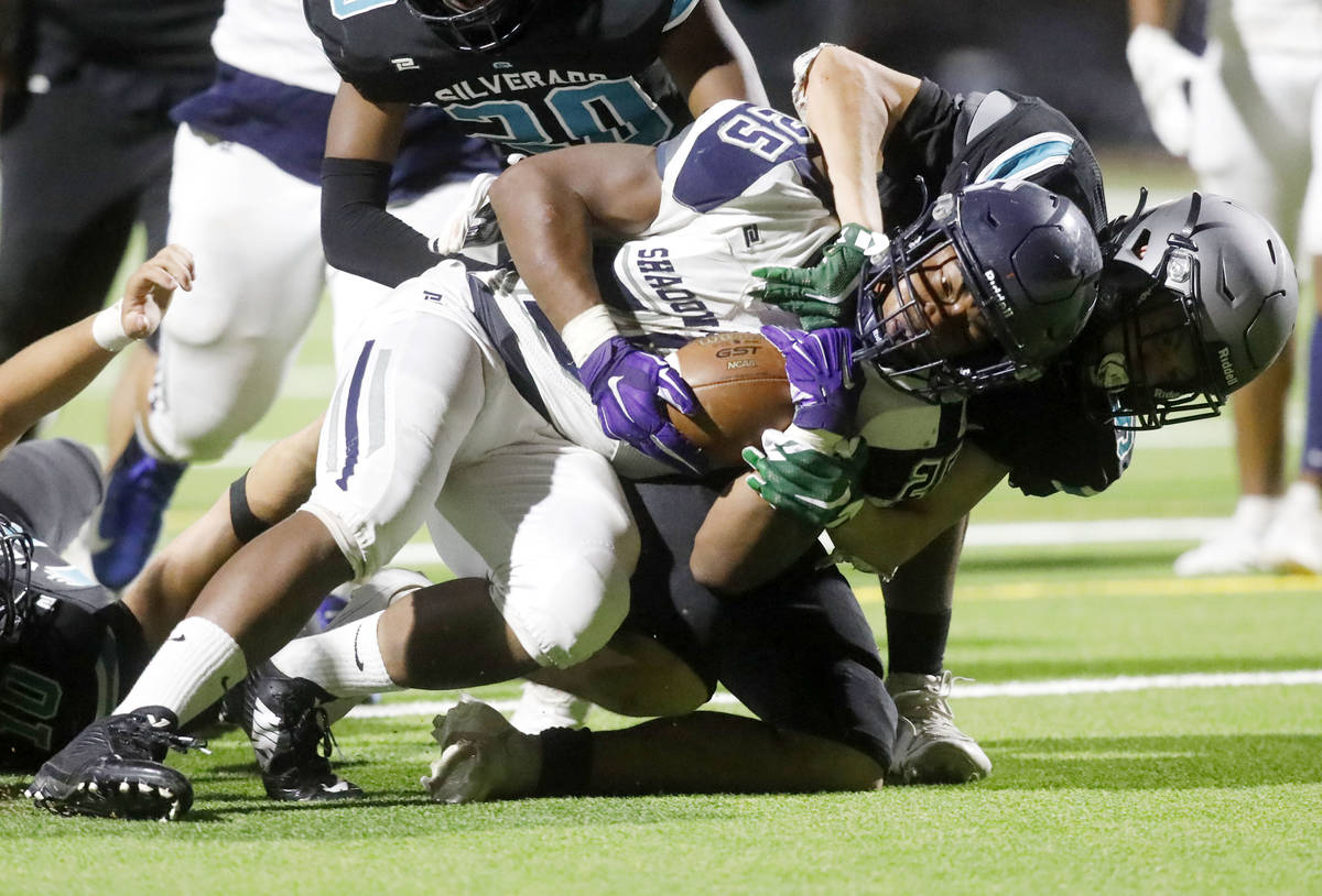 Shadow Ridge High School's Jaquieze Holland (25) is tackled by Silverado High School's Jaden Th ...