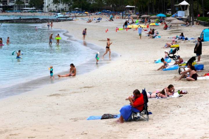 People gather on Waikiki Beach in Honolulu, Tuesday, Aug. 24, 2021. (AP Photo/Caleb Jones)