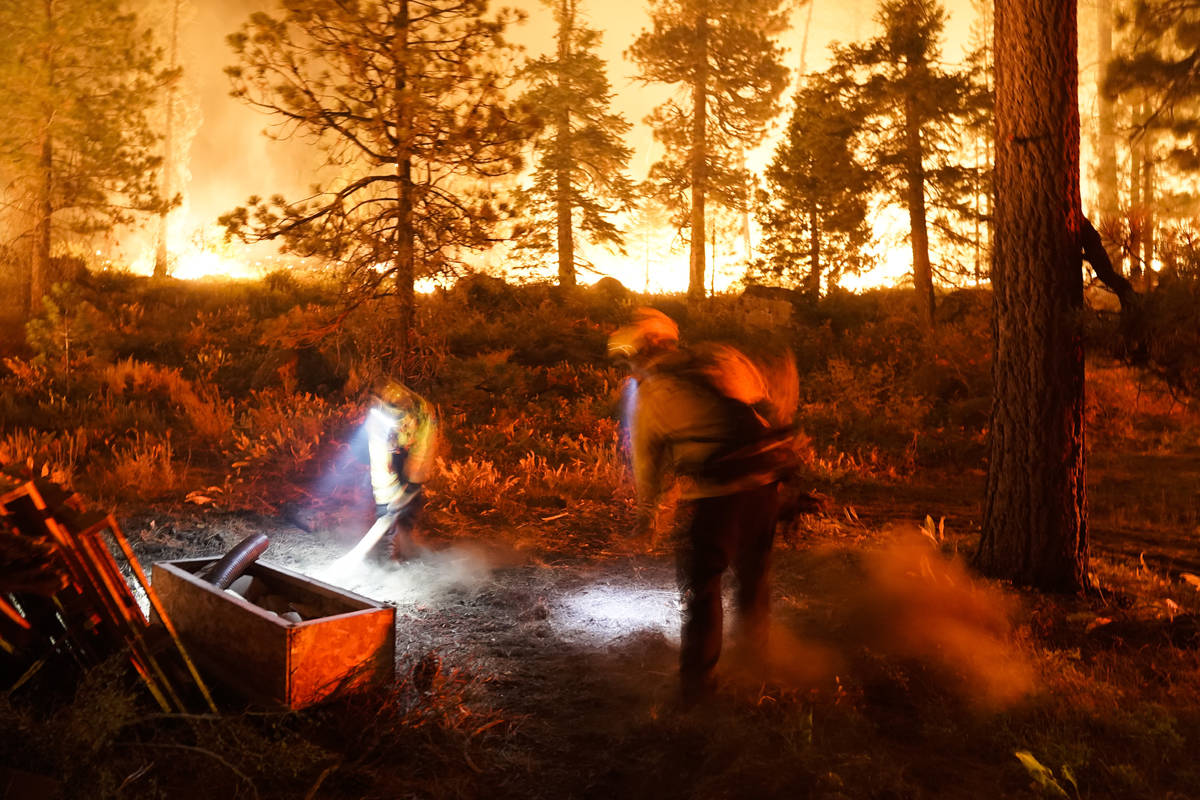 Two firefighters create a fuel break as the Caldor Fire burns near homes in South Lake Tahoe, C ...