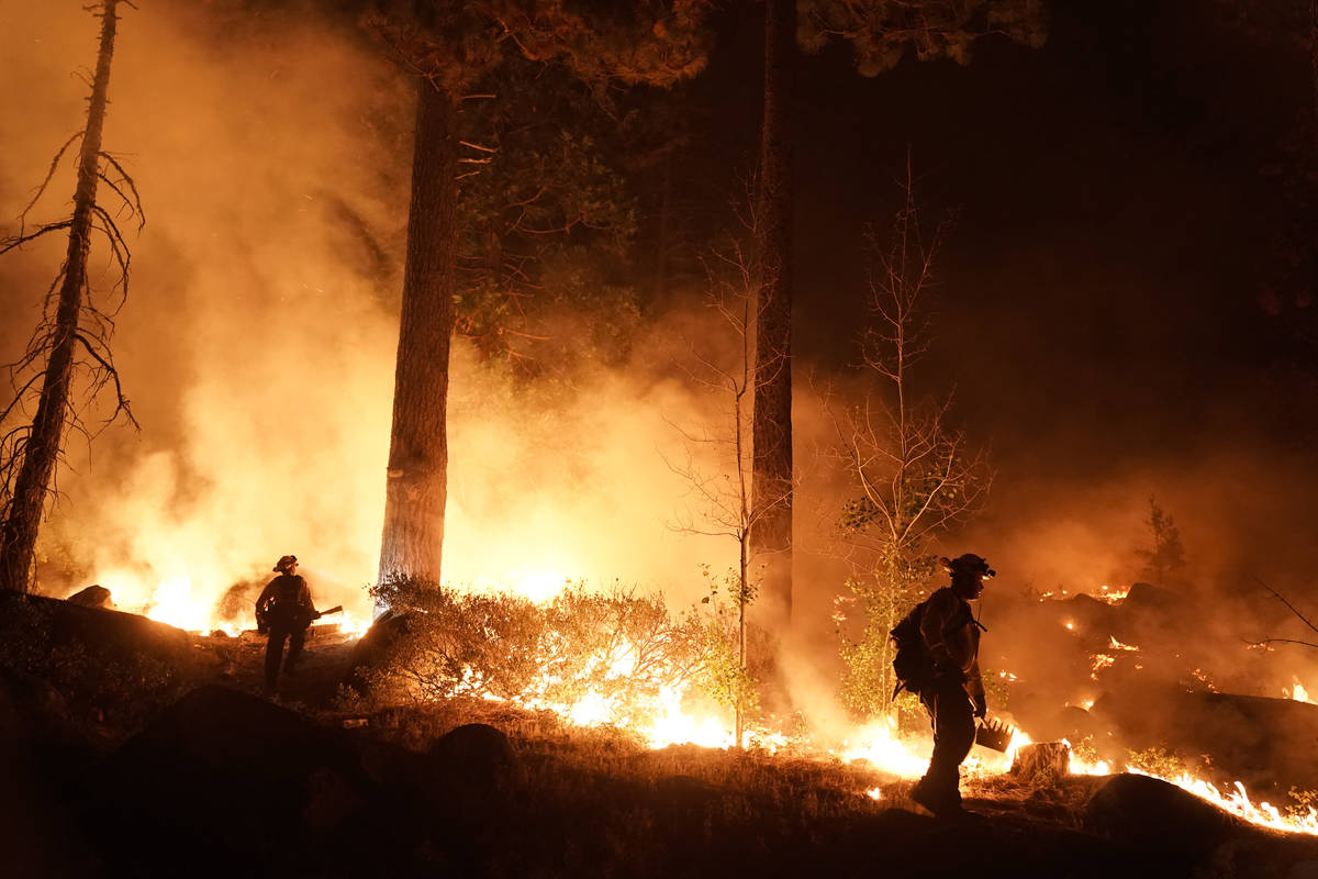 Two firefighters monitor the Caldor Fire burning near homes in South Lake Tahoe, Calif., Monday ...
