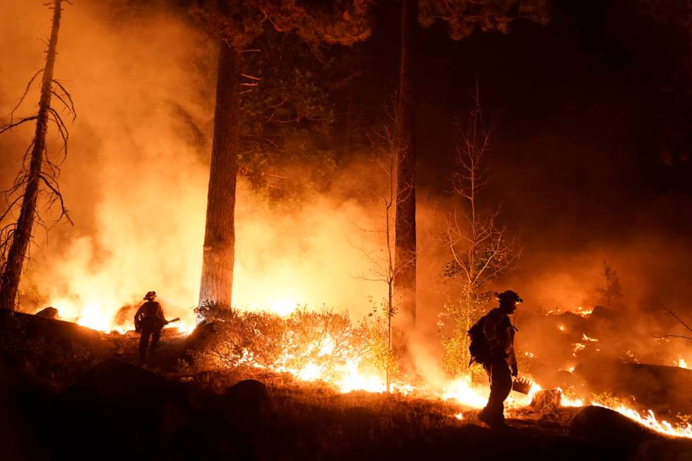 Two firefighters monitor the Caldor Fire burning near homes in South Lake Tahoe, Calif., Monday ...