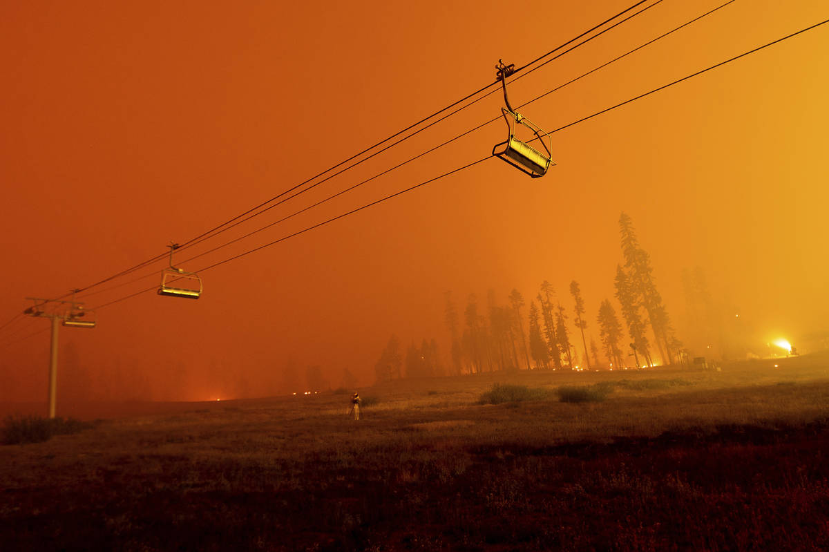 Seen in a long camera exposure, the Caldor Fire burns as chairlifts hang at the Sierra-at-Tahoe ...
