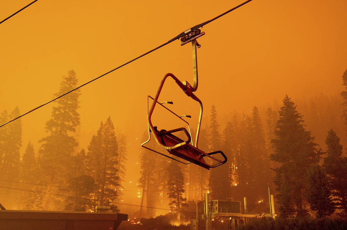 Seen in a long camera exposure, the Caldor Fire burns as a chairlift sits motionless at the Sie ...
