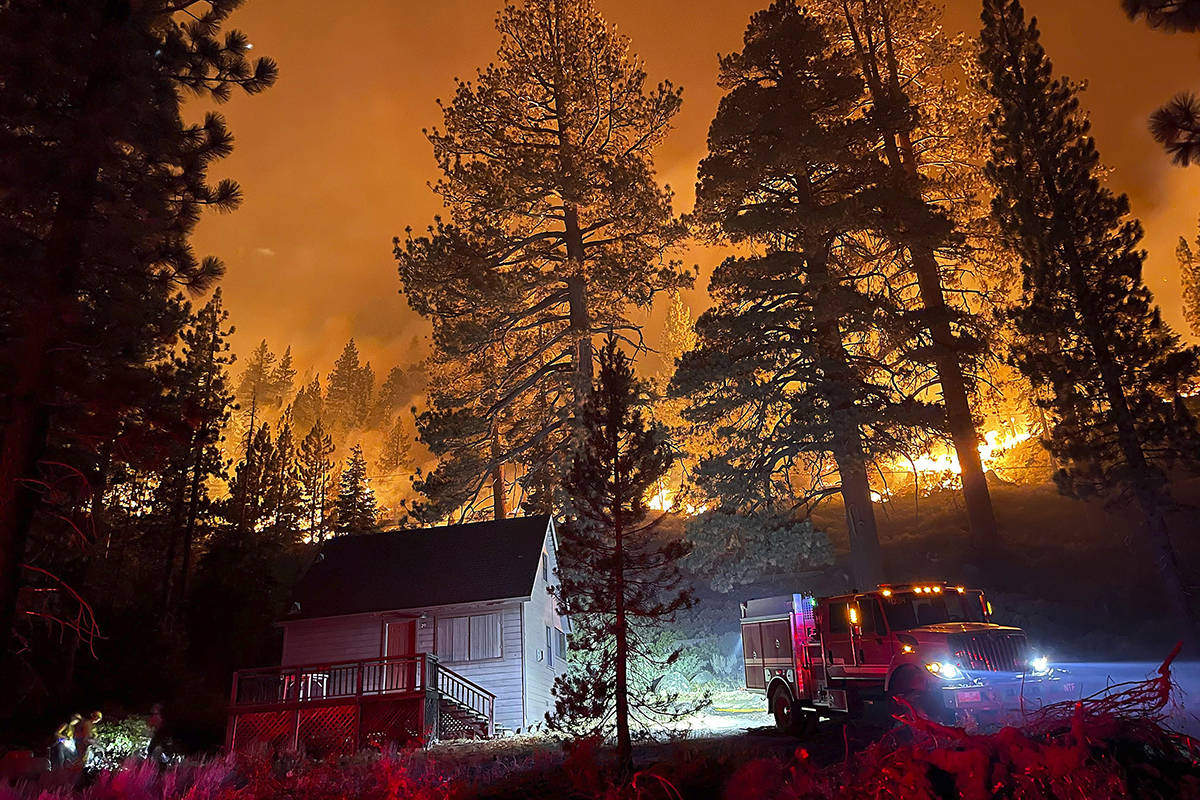 Firefighters protect a home from the Caldor Fire off of S. Upper Truckee Road in the Christmas ...
