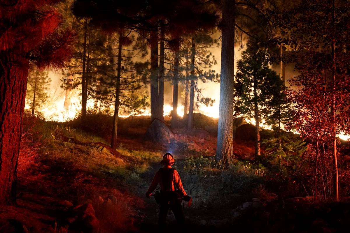 A firefighter monitors the Caldor Fire burning near homes in South Lake Tahoe, Calif., Monday, ...